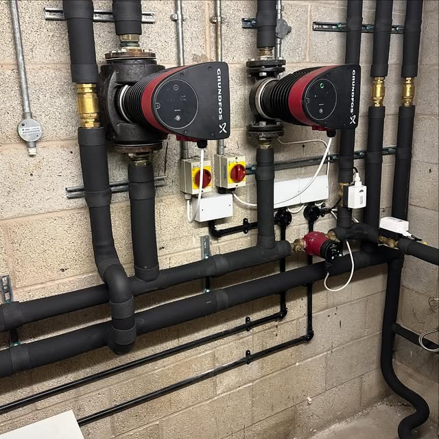 Twin Grundfos pumps on an insulated flow and return header